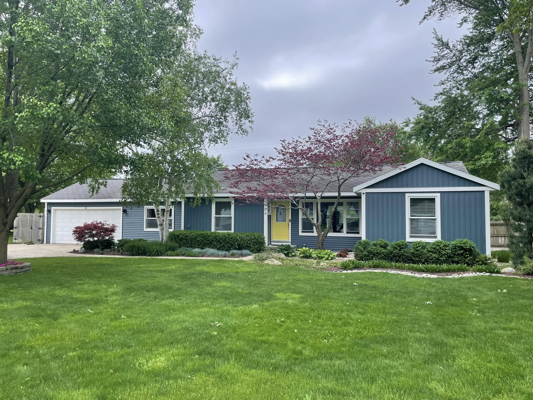 Remodeled backyard home with updated blue siding and enhanced landscaping.
