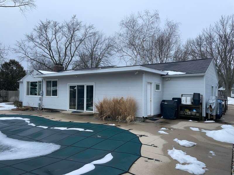 Small backyard home with faded white siding and minimal landscaping