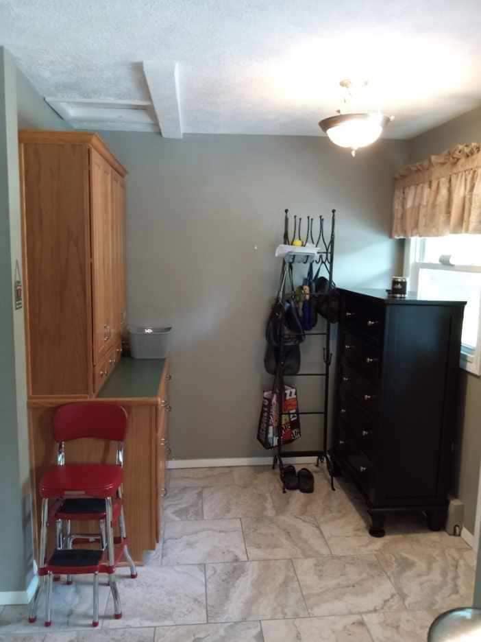 Small kitchen area with dated wooden pantry cabinet and dark wall color.
