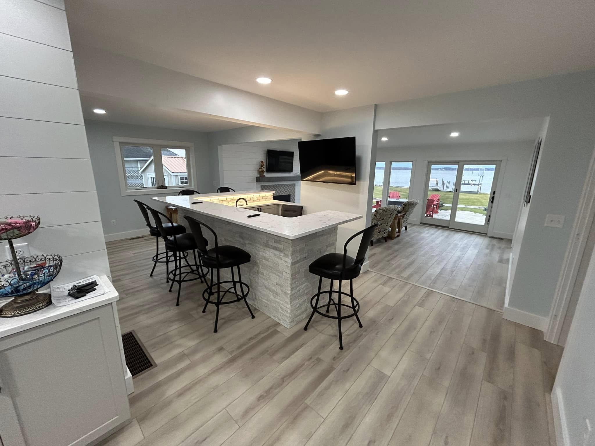 Open-concept living area with wood floors, new lighting, and updated fireplace by Vanderlee Construction, LLC