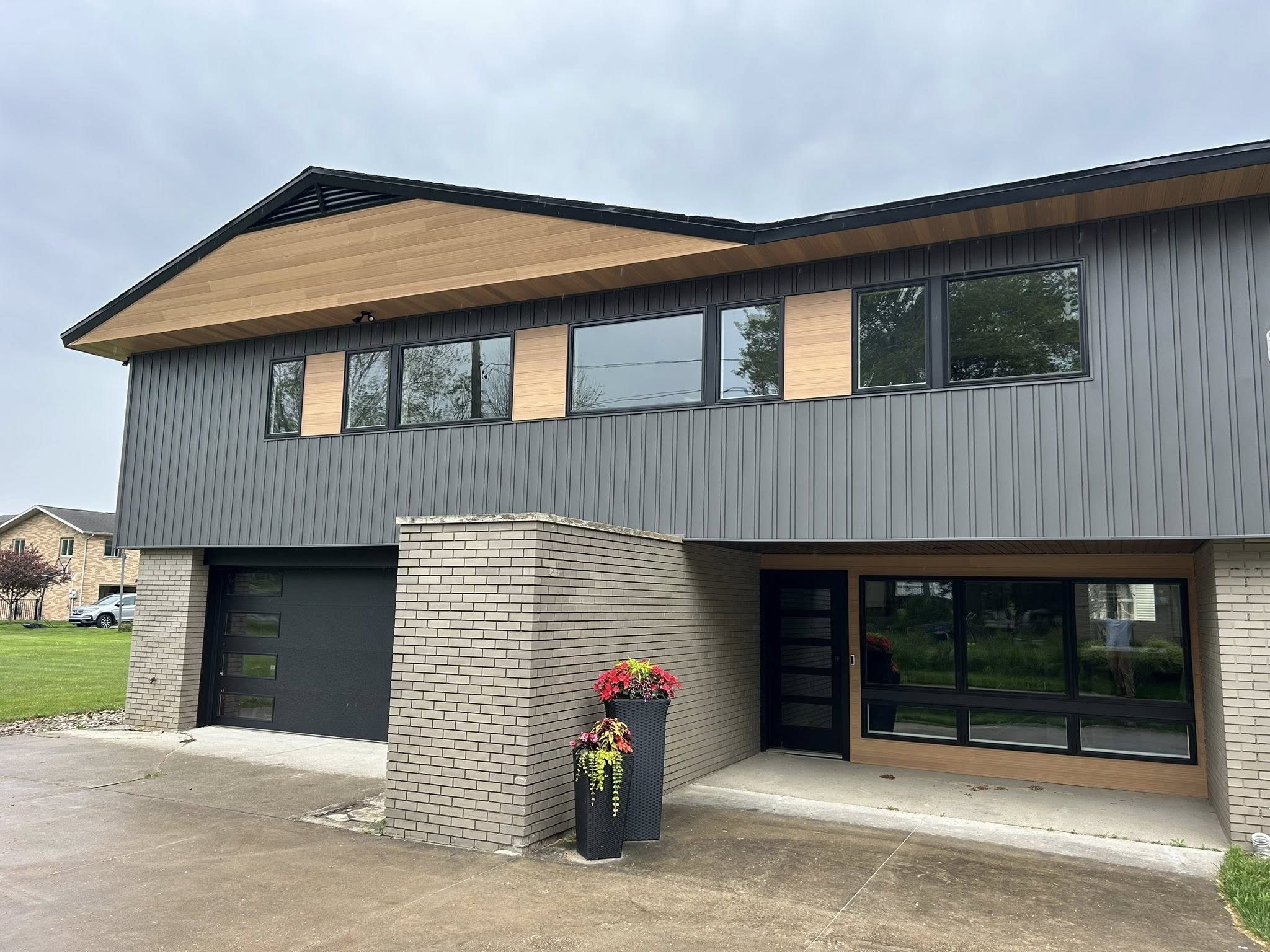 Renovated split-level home with sleek vertical gray siding and contemporary black window trim
