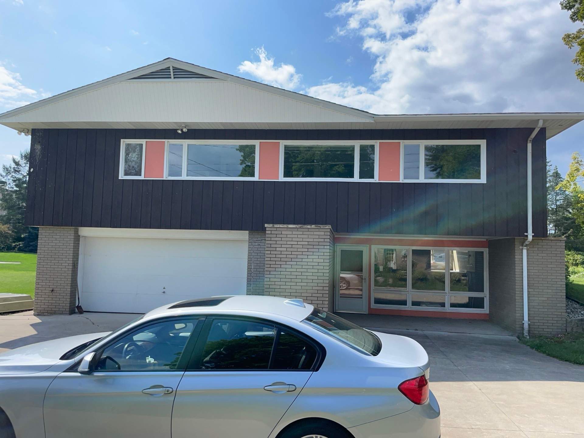 Two-story home with faded beige siding and outdated exterior design.