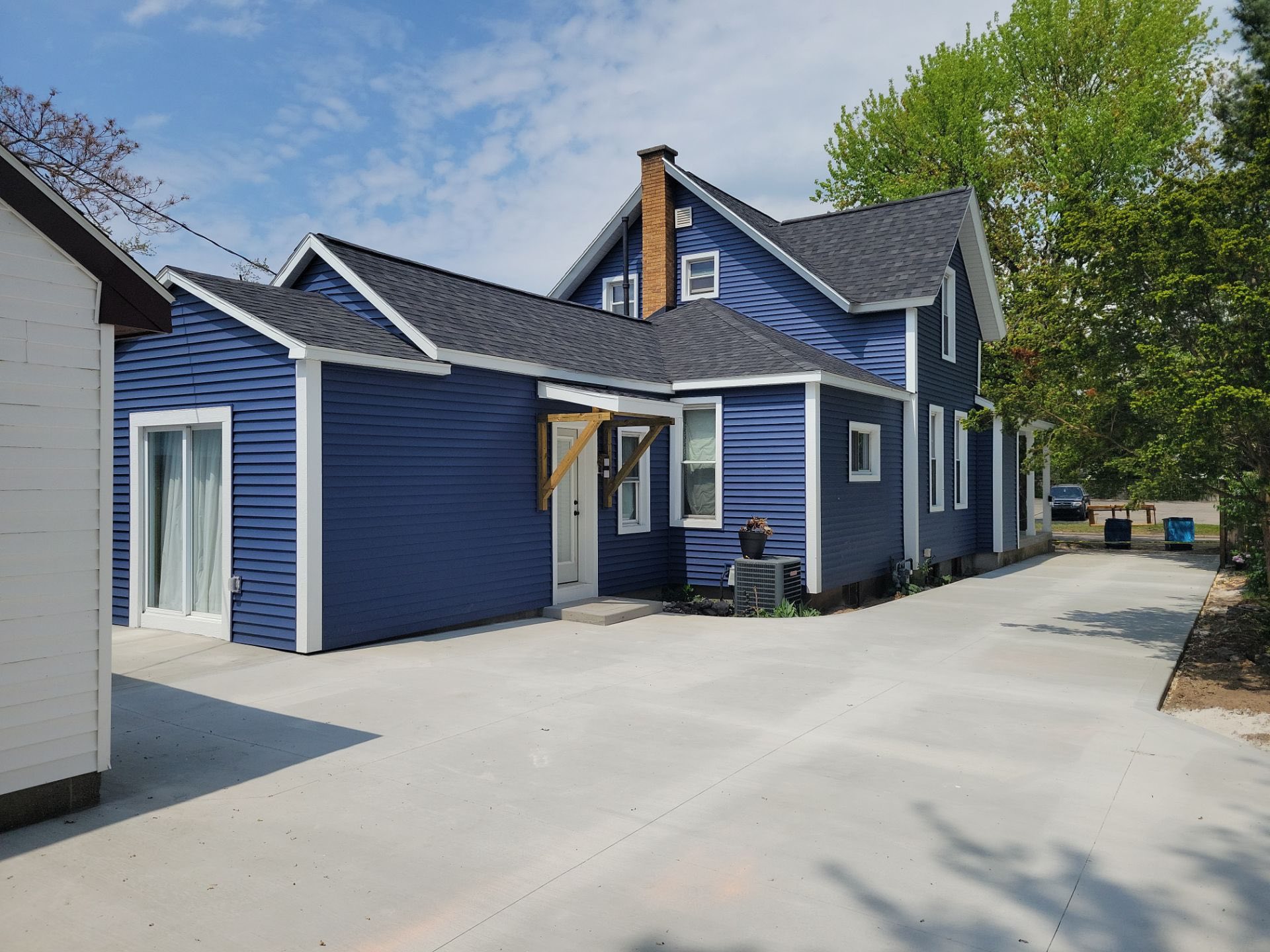 Updated exterior featuring dark blue siding, white trim, and new driveway for improved curb appeal